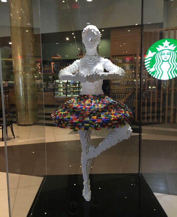 LEGO ballerina sculpture in a colorful tutu, displayed in a glass case at a Starbucks. Cool-LEGO-Builds.