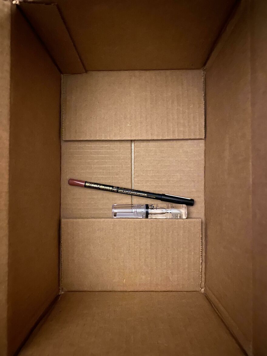 Large cardboard box with small makeup items inside, illustrating wasteful unnecessary packaging.