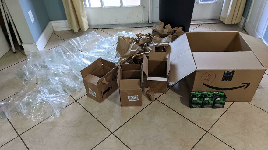 Excessive packaging waste with multiple boxes and plastic fillers for small items on a tile floor.