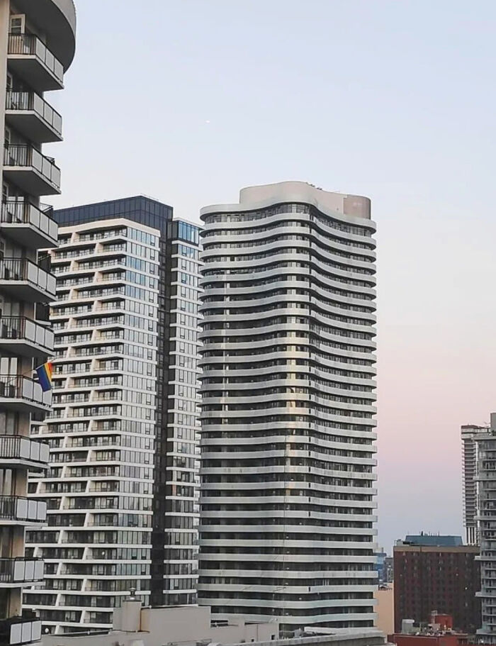 Confusing perspectives of wavy skyscrapers against a clear sky.