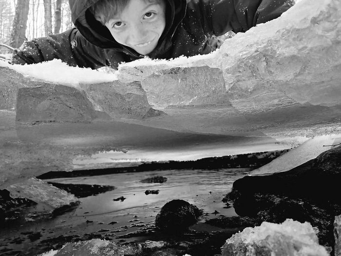 Confusing perspective of a child peering through layers of ice with a reflective surface below.