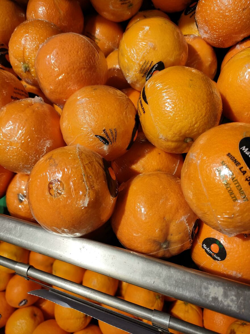 Oranges covered in plastic wrap, showcasing wasteful unnecessary packaging.