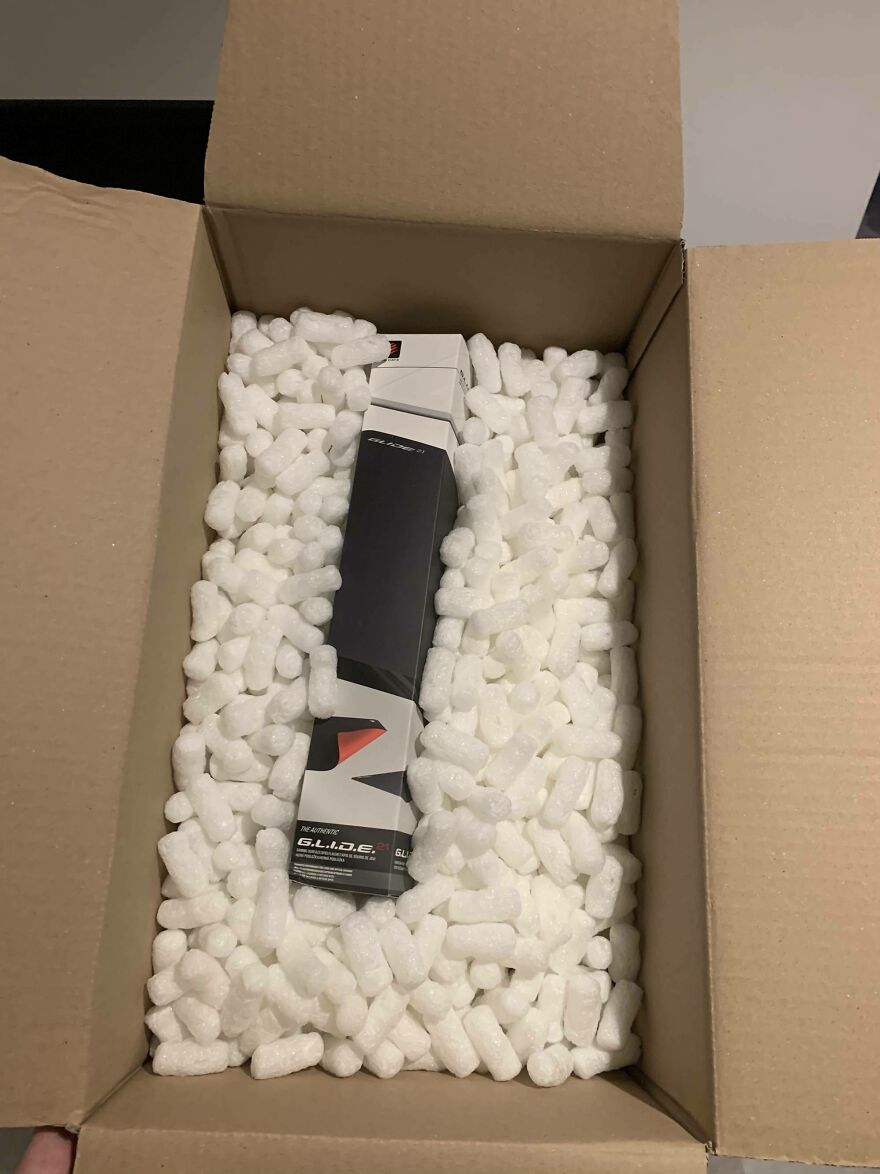 A small product box surrounded by excessive packing peanuts, illustrating wasteful packaging practices.