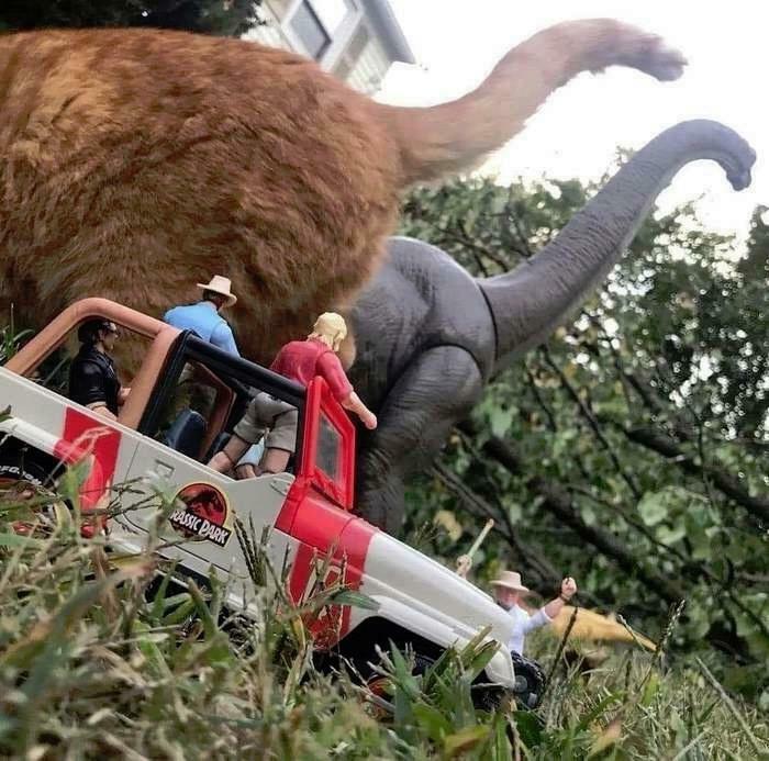 Toy figures in a Jeep with a cat and dinosaur create a confusing perspective scene.