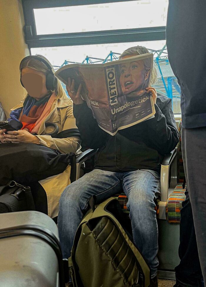 Man reading newspaper with confusing perspective, creating optical illusion on a train.