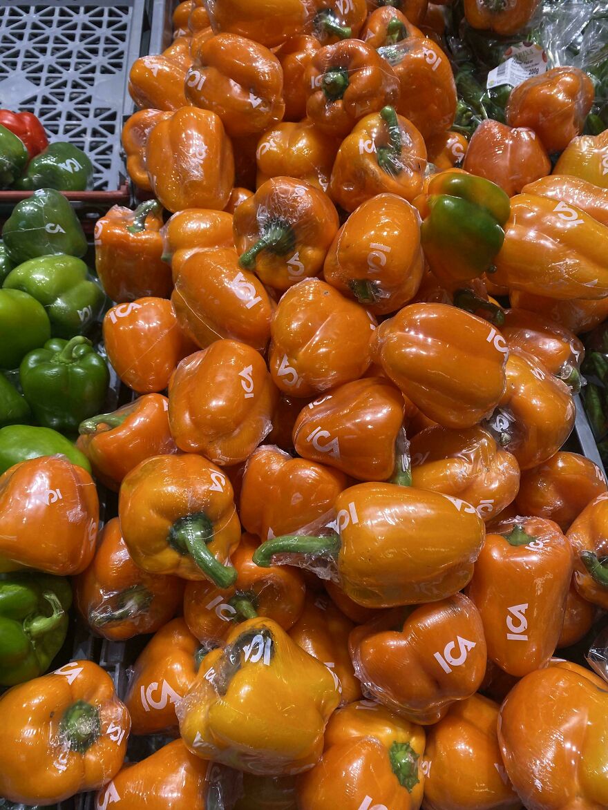 Orange bell peppers with wasteful packaging in plastic wrap.