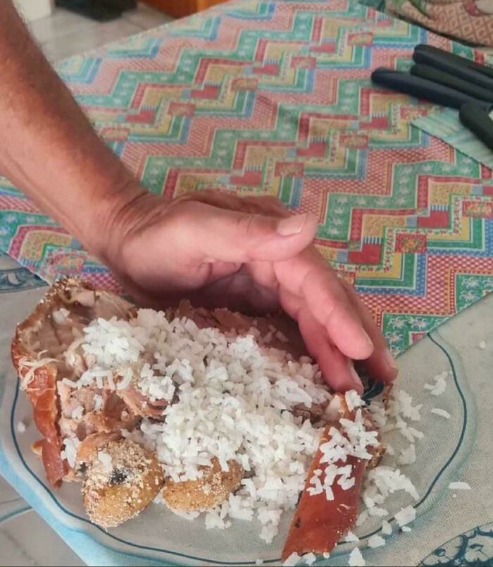 Confusing perspective: a hand appears to shape rice piled on a plate, creating an unusual visual illusion.