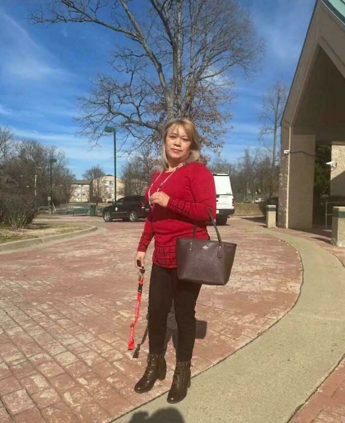 Woman in red sweater standing in a park with confusing perspective; shadow creates an unusual optical illusion.