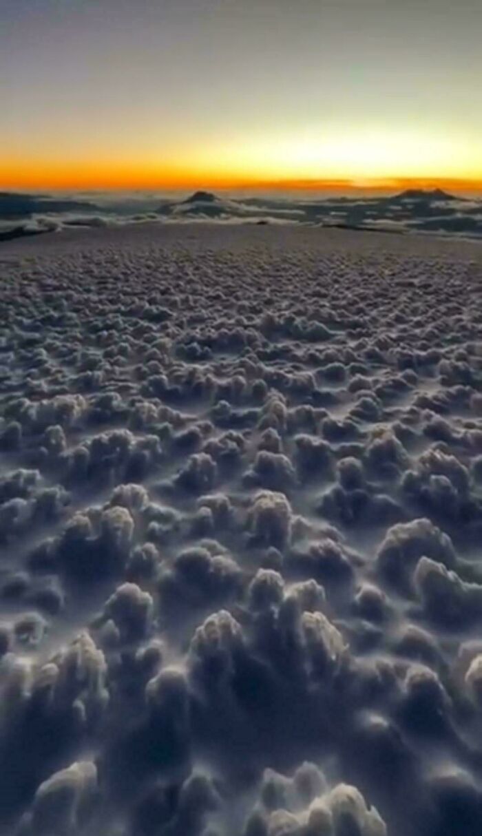 Confusing perspective showing fluffy clouds appearing like a snow-covered landscape at sunset.