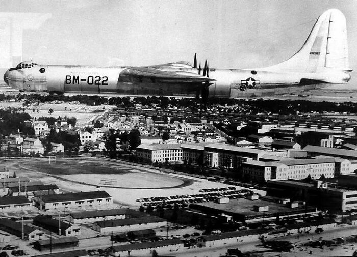 Confusing perspective of a large aircraft appearing to fly low over a cityscape, creating an optical illusion.