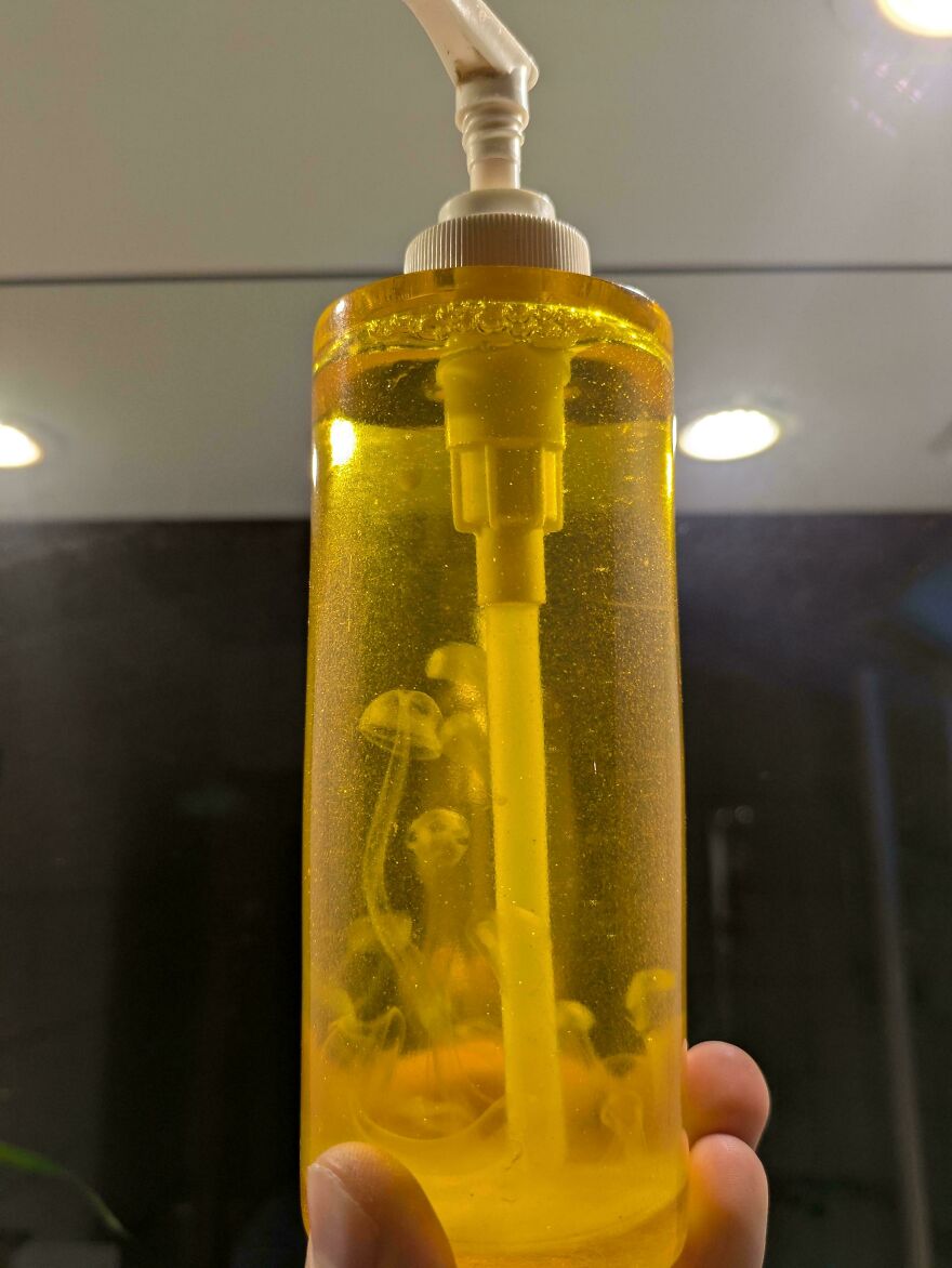 Soap dispenser containing liquid, with floating jellyfish-like shapes inside.