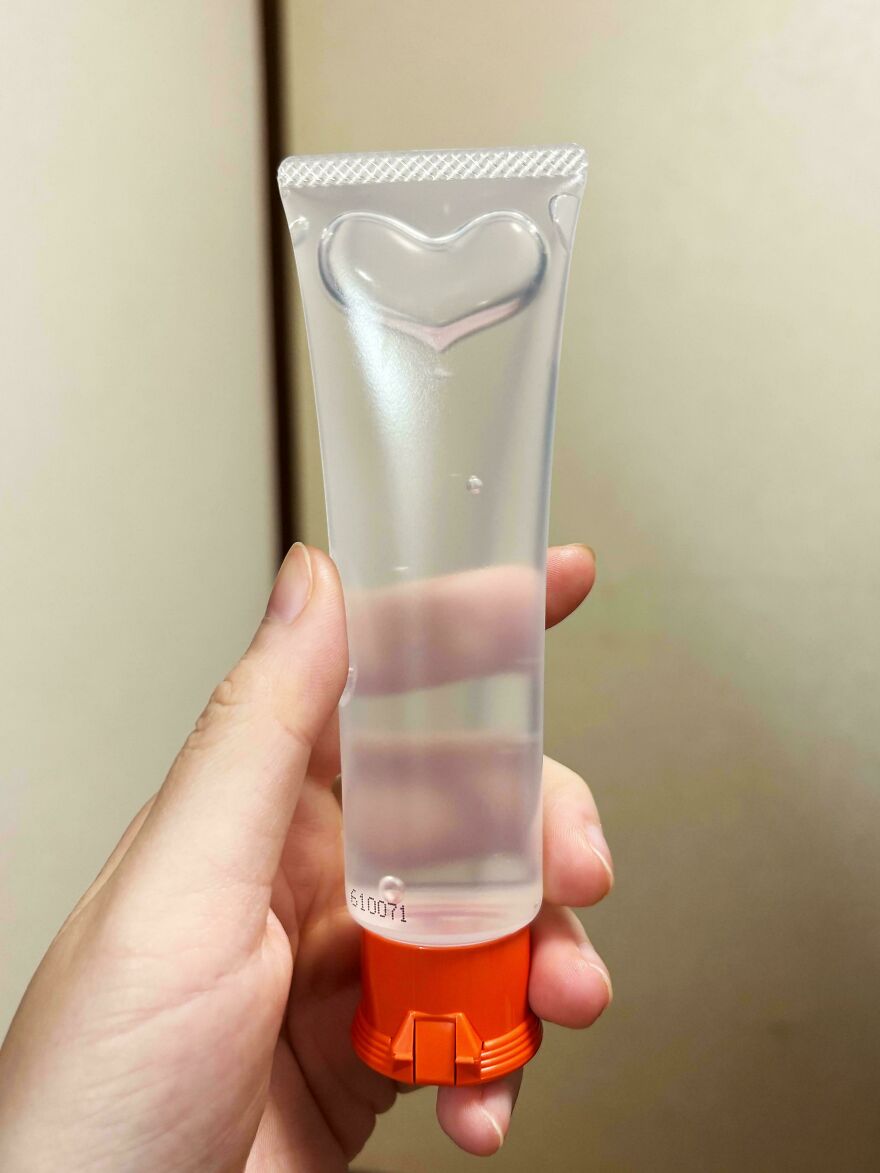 Hand holding a clear tube with a heart-shaped infuser, looking like a toothpaste tube.