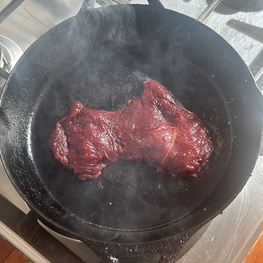 Steak resembling the shape of a U.S. state sizzling in a cast iron pan.