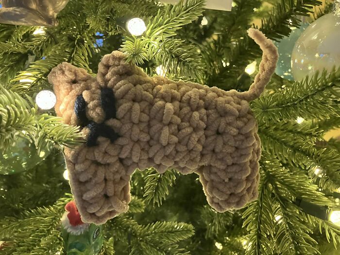 Crocheted dog ornament hanging on a Christmas tree branch, showcasing incredible crochet craftsmanship.