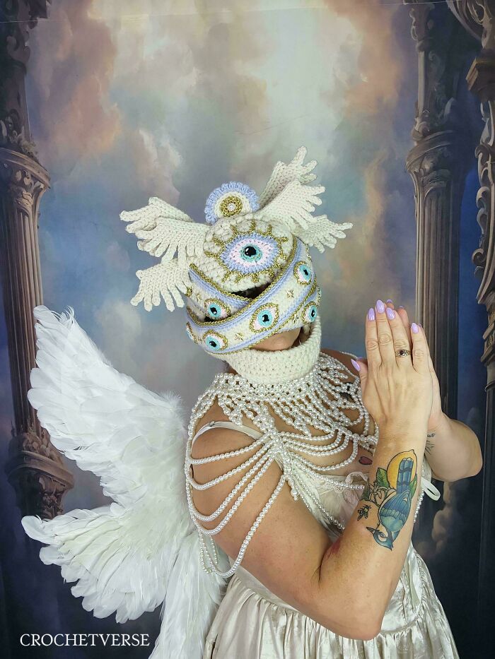 Woman wearing elaborate crocheted costume with wings and multiple eye details.