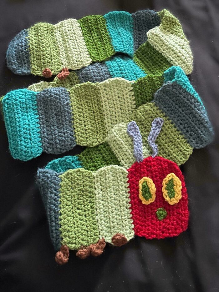 Crocheted scarf featuring a colorful caterpillar design on a black background.