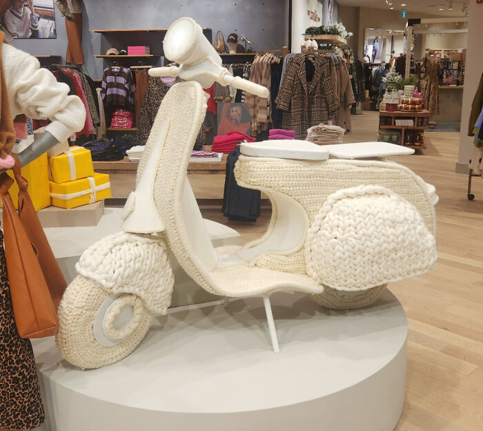 A scooter covered in intricate crochet displayed in a clothing store, showcasing creative crocheted designs.