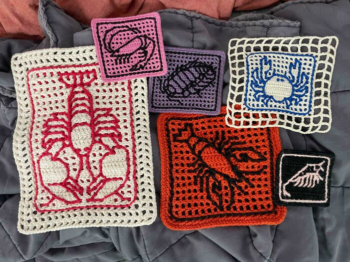 Crocheted squares with sea creature designs in vibrant colors displayed on a fabric background.