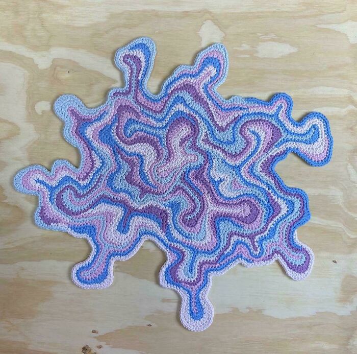 Intricate crocheted design with swirling pastel patterns on a wooden background.