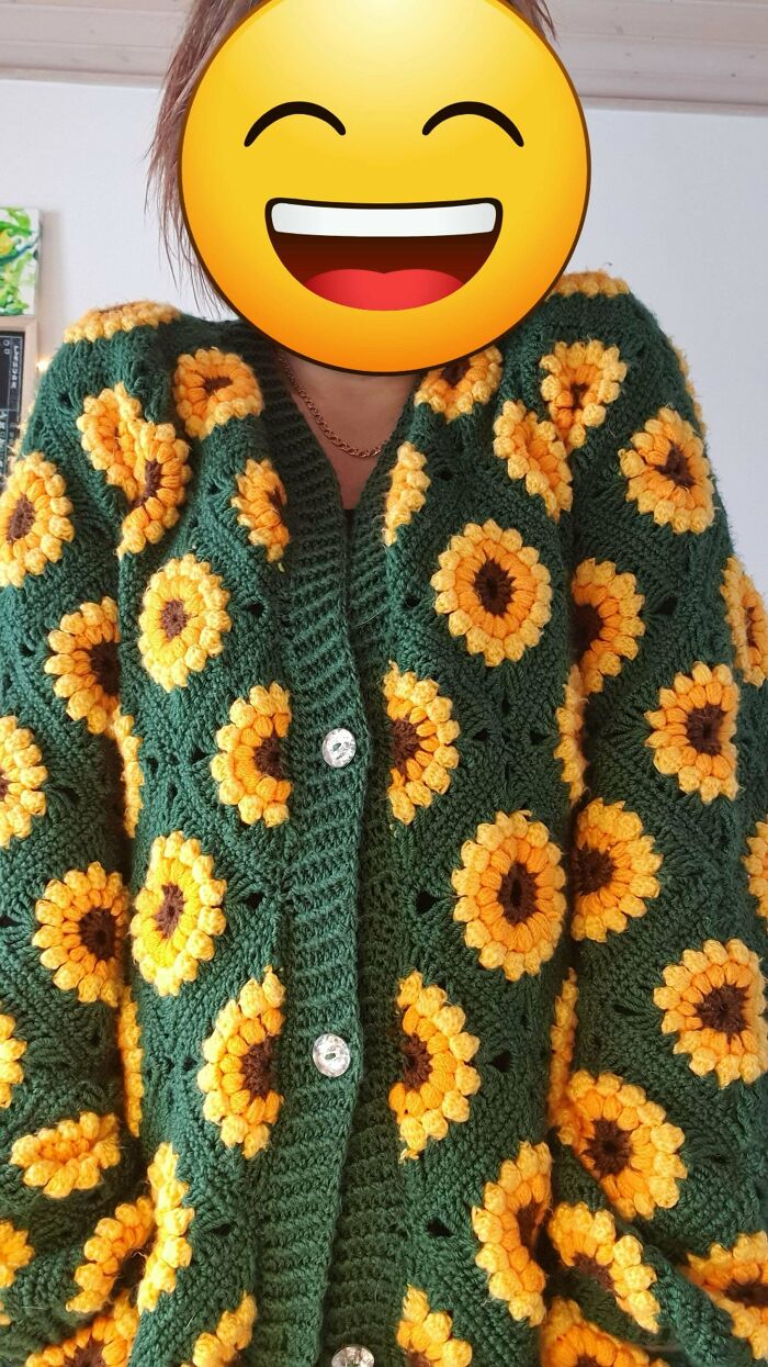 Crocheted green sweater with yellow sunflower patterns.