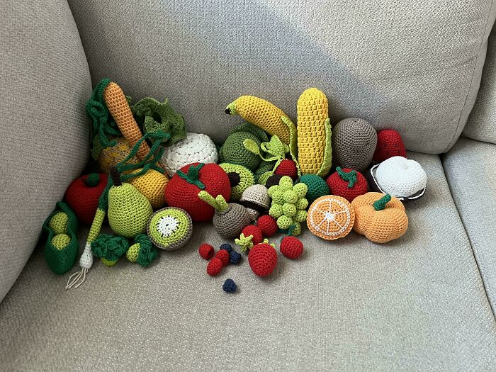 Crocheted fruits and vegetables on a couch, showcasing incredible crochet artistry.