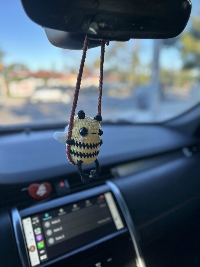 A crocheted bee hanging from a car mirror, showcasing creative crochet skills.