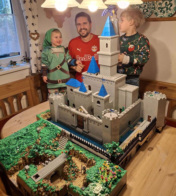 A family admires a large, detailed LEGO castle on a table, representing cool LEGO builds.