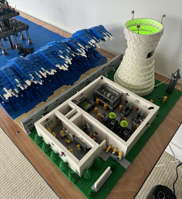 Cool LEGO build featuring a nuclear power plant, ocean waves, and detailed interior rooms with LEGO figures.