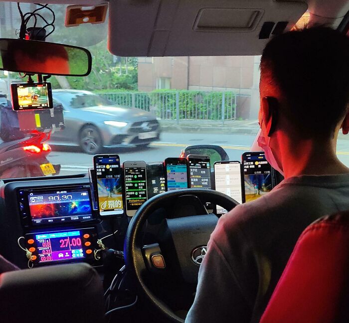 Driver with multiple phones mounted on the dashboard, illustrating a risky setup in a car.