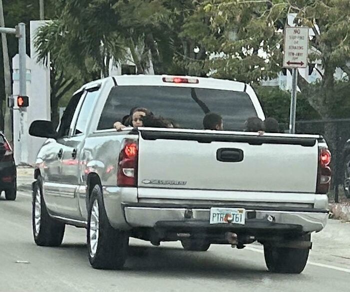 Pickup truck with people sitting unsafely in the bed, illustrating risky behavior on the road.