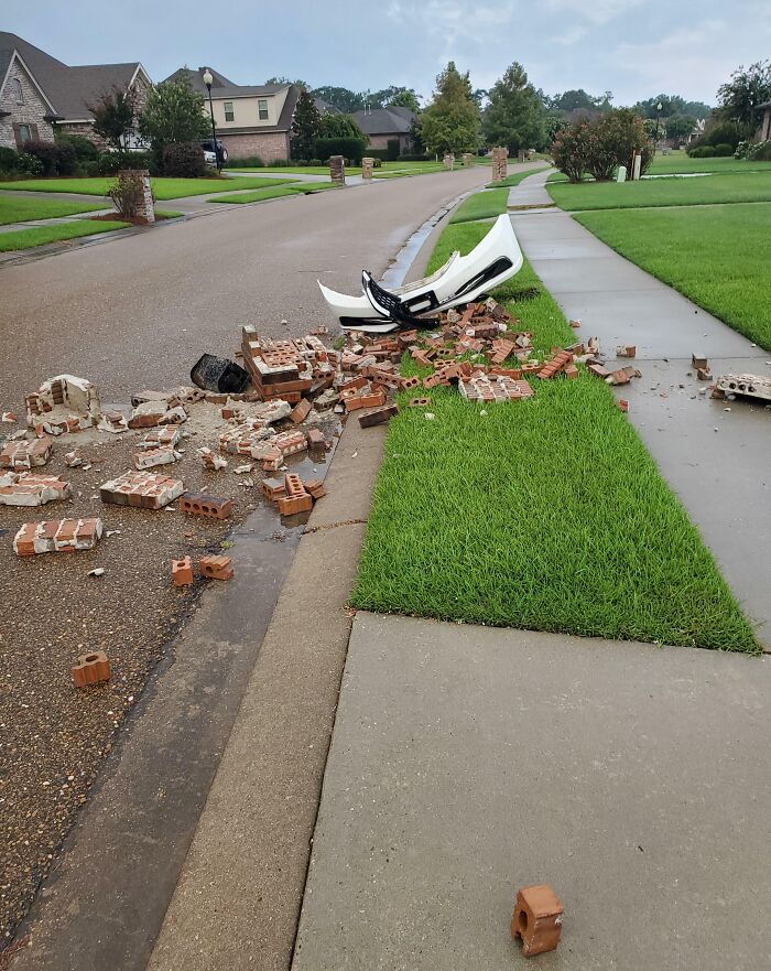 Car parts and bricks scattered on suburban street, likely from careless driving incident.