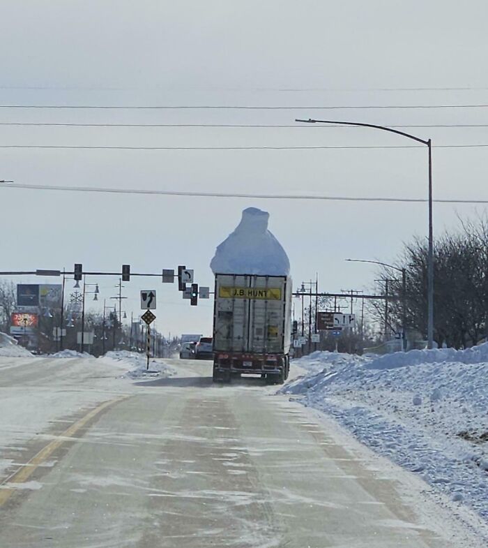 Truck driving with a large pile of snow on top, illustrating a classic example of idiots in cars.