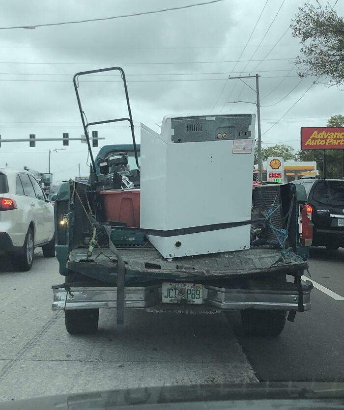 Truck overloaded with unsafe cargo on a busy road, highlighting hazardous driving behavior.