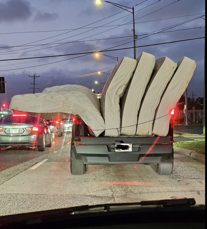 Car loaded with multiple mattresses precariously tied, a classic example of idiots in cars on a busy street.