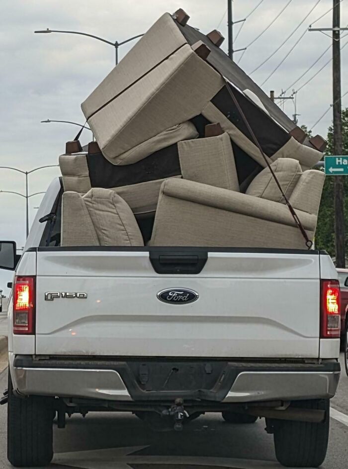 Pickup truck overloaded with furniture, illustrating dangerous driving behavior often seen with idiots in cars.