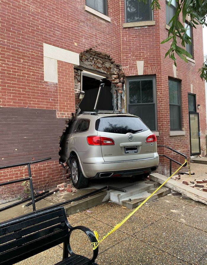 Car crashed into a brick building, illustrating risky driving behavior.