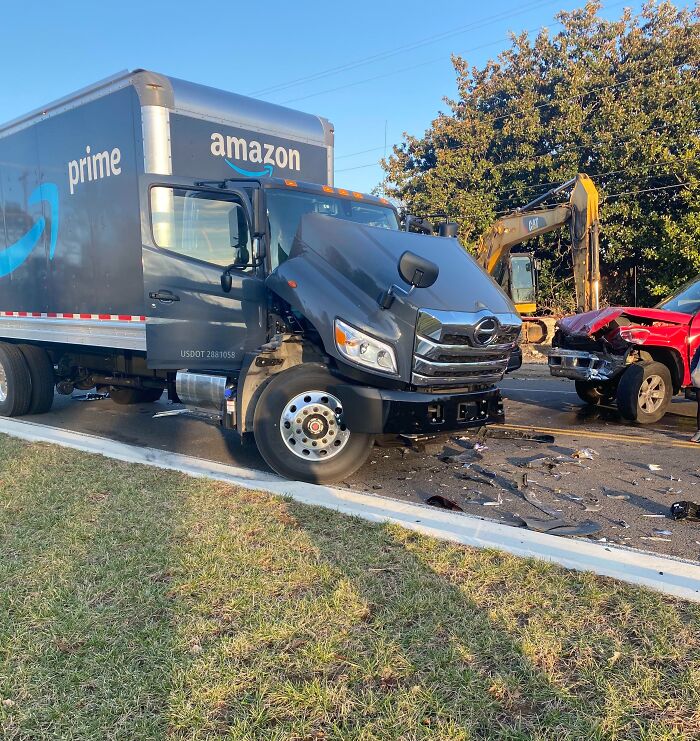 Amazon truck and red pickup collide on road, with visible front-end damage.