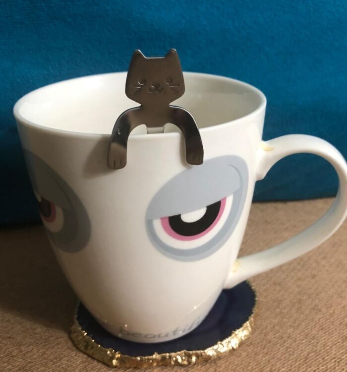 Cute cat-shaped novelty tea infuser perched on a mug with whimsical eye design.