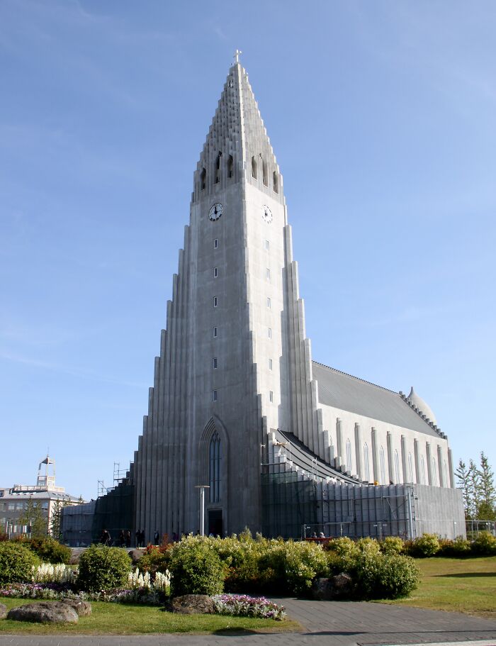 Fascinating church photo of a tall, modern concrete church with a striking tower and clock, set against a clear blue sky.