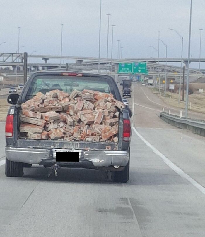 Truck overloaded with bricks on a highway, illustrating dangerous driving from "Idiots-In-Cars" scenarios.