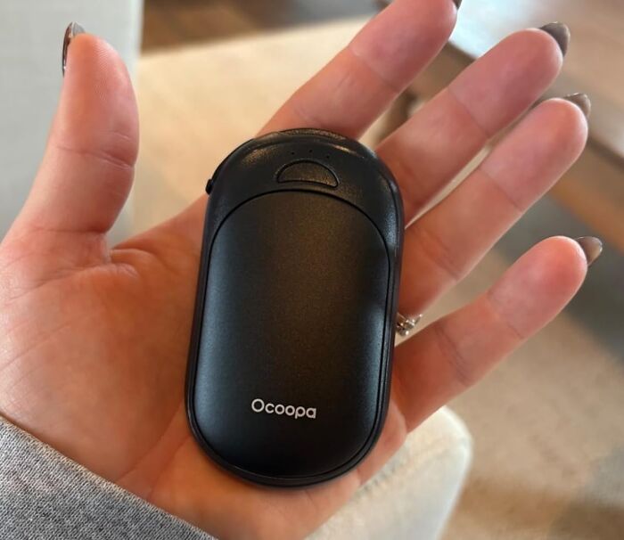 Hand holding a black Ocoopa hand warmer, showcasing one of the biggest discounts on Amazon winter deals.