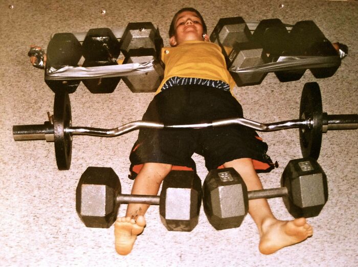 Child playfully surrounded by weights, capturing a funny-camera-roll-finds moment.