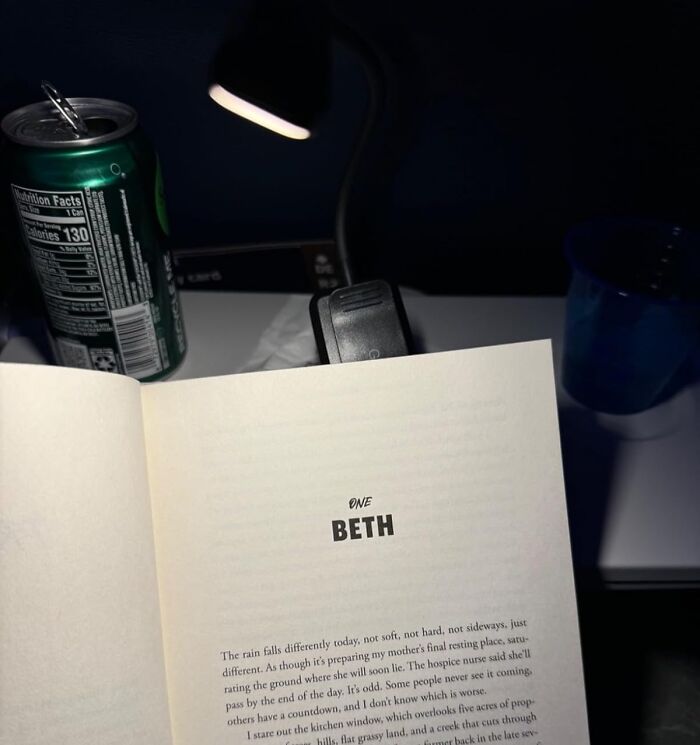 Book page under reading light, next to a can and a cup, related to Amazon winter deals discounts.