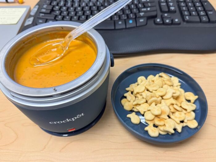 Crockpot with soup and a plate of crackers on a desk, ideal product for Amazon winter deals discounts.