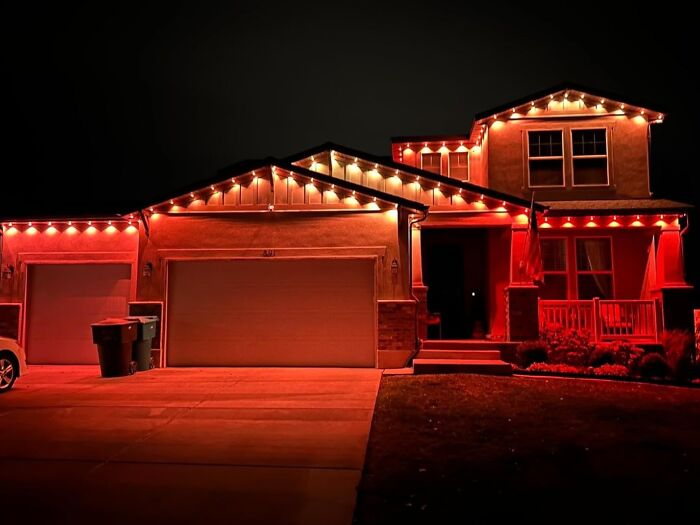 A house illuminated with red and white lights for winter, showcasing festive decor.