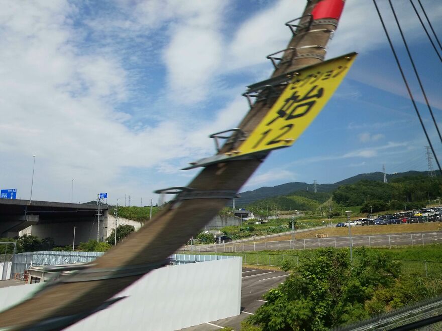 Blurred photo capturing a diagonal pole with a yellow sign in a scenic landscape, an example of accidental art.