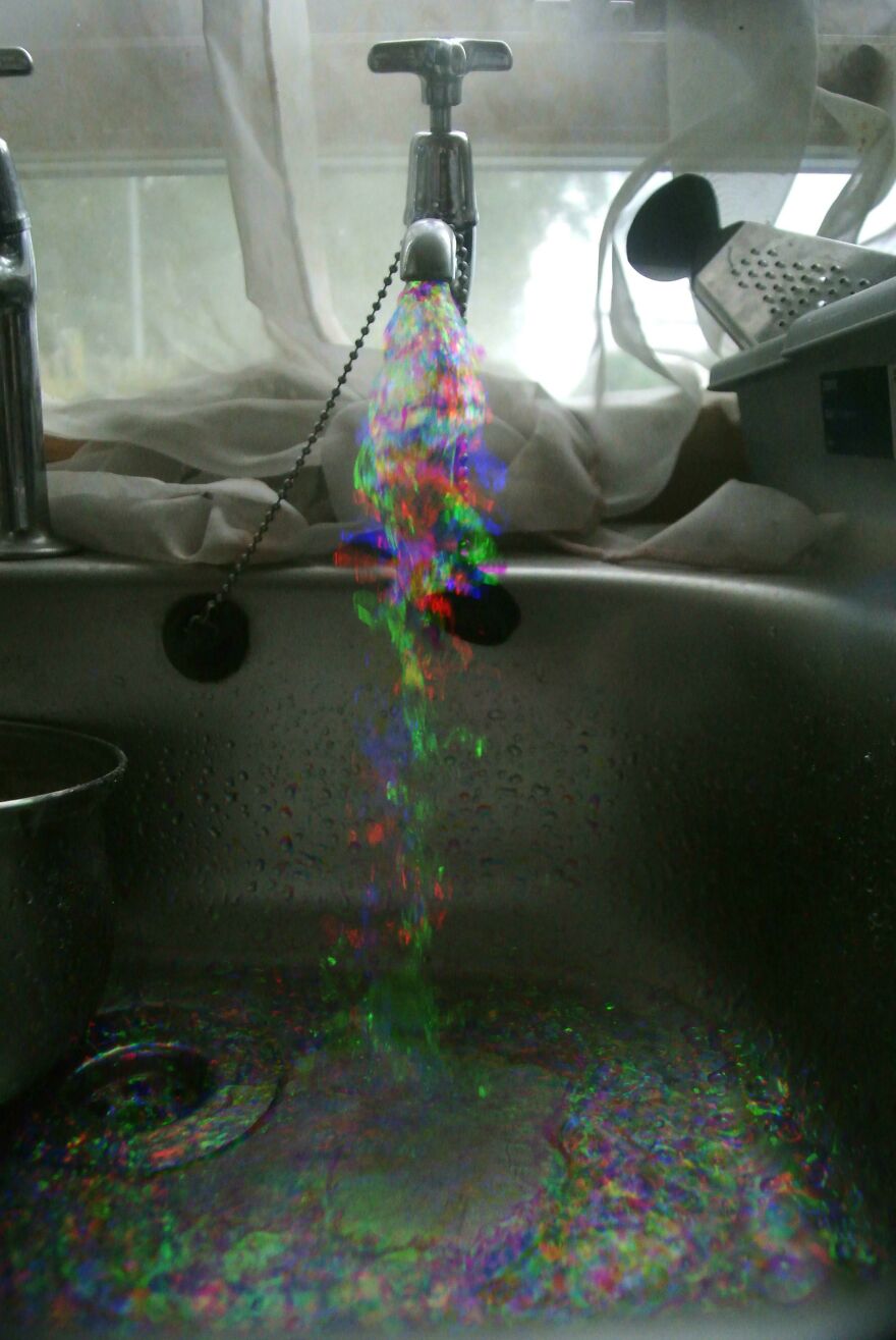 Colorful water stream creating accidental art in a kitchen sink.