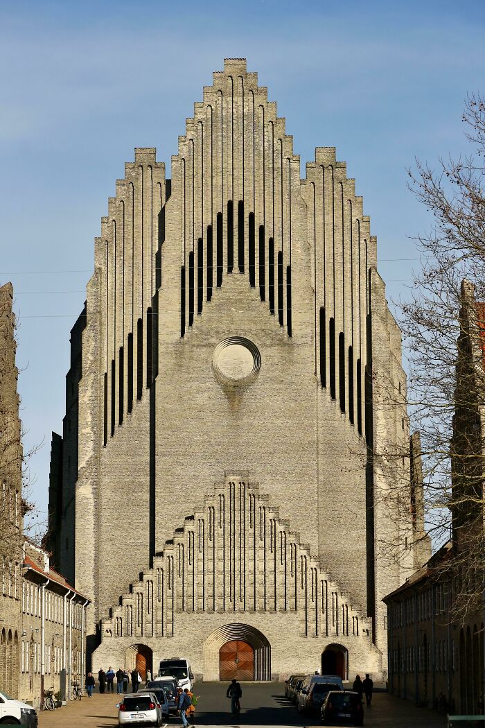 Impressive architecture of a large brick church facade under a clear blue sky, showcasing unique geometric design.