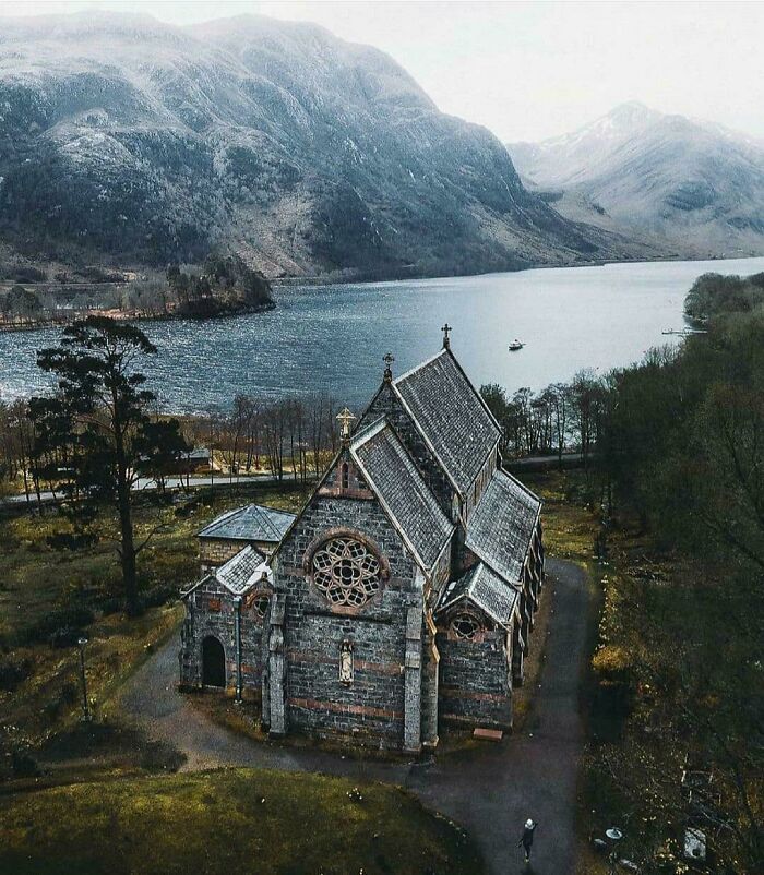 Aerial view of a fascinating church near a scenic lake and mountain landscape.