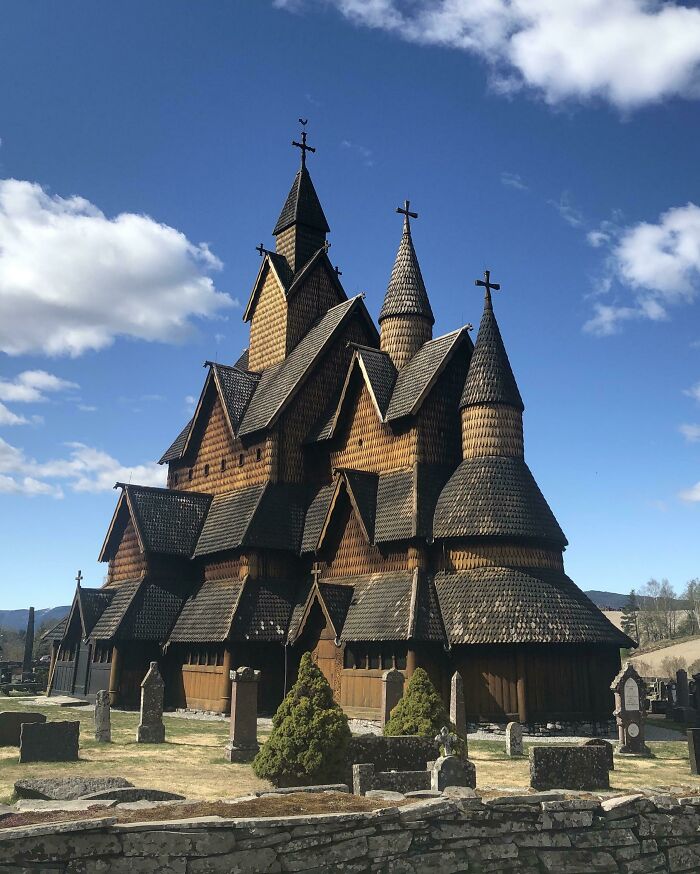 Historic wooden stave church under a bright blue sky, showcasing intricate architecture.